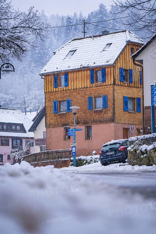 A yellow house with wooden panelling and blue shutters in the snow, Enzklösterle, Calw district, Black Forest, Germany, Europe