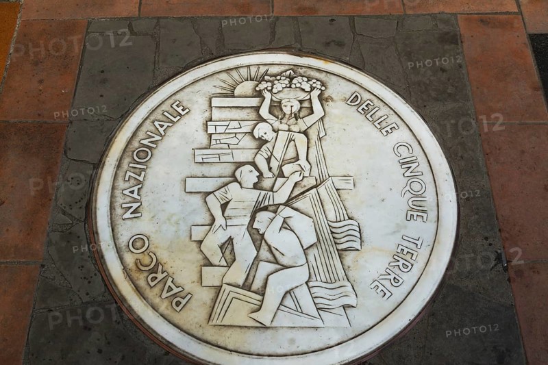 Round white marble plaque inscribed with the Italian words Parco Nazionale Delle Cinque Terre inlaid in paving stones, Manarola, Cinque Terre, La Spezia province, Italy, Europe
