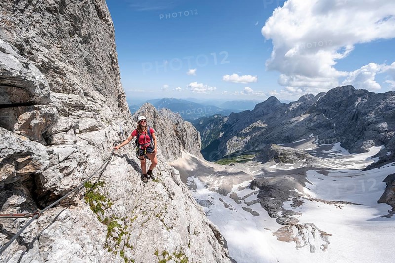 Mountaineer with helmet in a secured via ferrata, Zugspitz via ferrata, ascent to the Zugspitze, view of mountain basin with snowfield of the Höllentalferner and Höllental, Wetterstein range, Bavaria, Germany, Europe