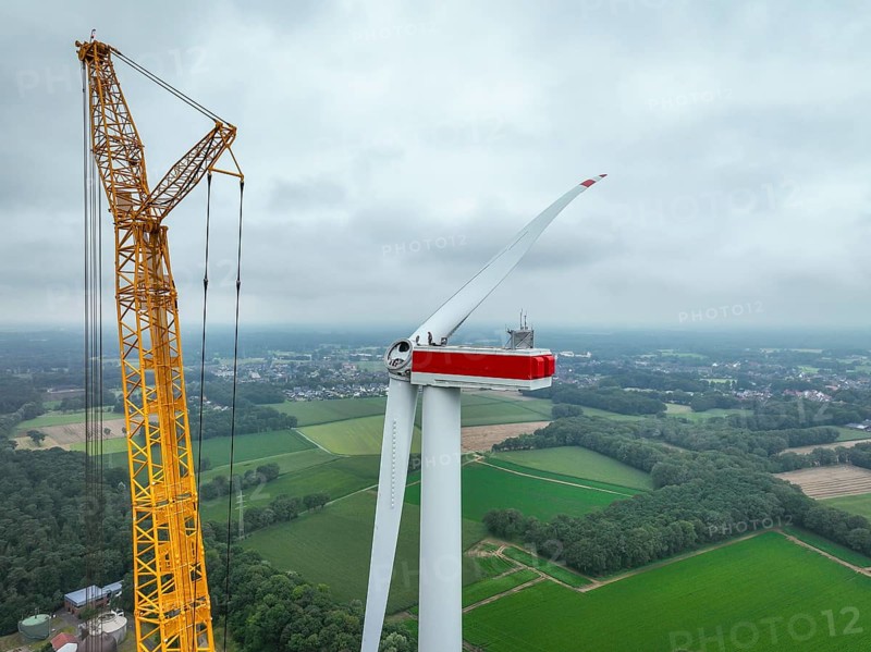Dorsten, North Rhine-Westphalia, Germany, construction of a wind turbine. A large mobile crane lifts a rotor blade to the nacelle on the tower. Here, the blade is mounted directly on the motor hub. Große Heide wind farm, Europe