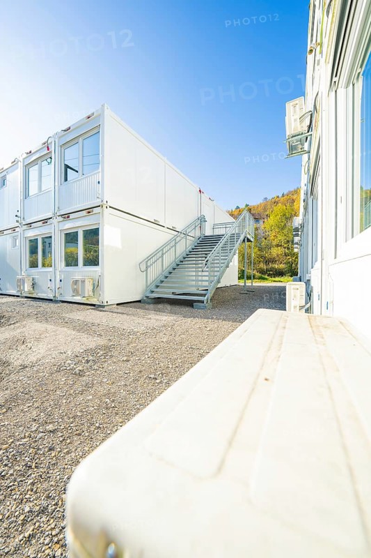 Container building with access stairs and autumn forest in the background, under a clear sky, refugee accommodation Beermiß, Calmbach, Black Forest, Germany, Europe