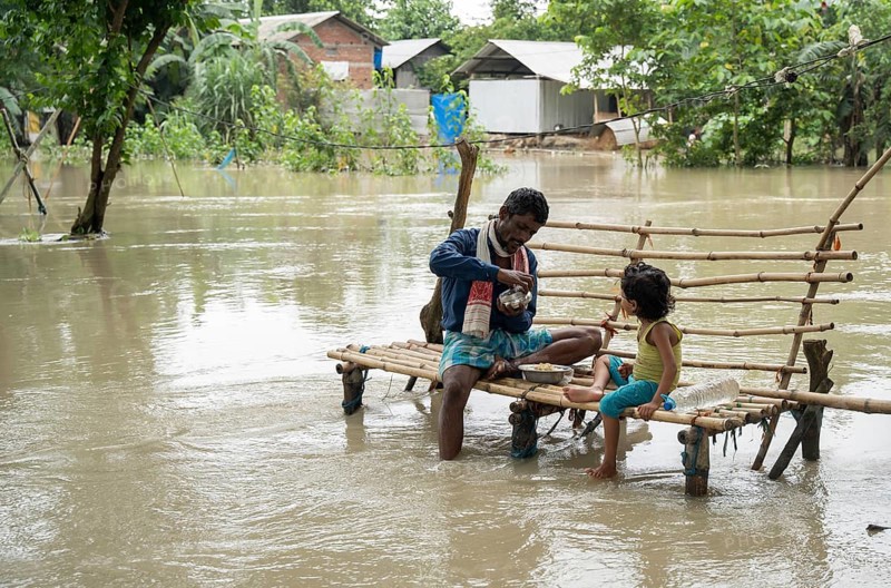 Morigaon, India. 4 July 2024. Father with his daughter eating food, in a flood affected village in Morigaon district in India's northeastern state of Assam on July 4, 2024. Torrential rains and surging rivers across northeast India have killed at least nine people, with more than 1.5 million people affected