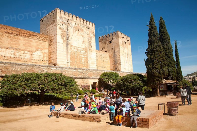 Fortified walls of the Alcazaba castle in the Alhambra complex, Granada, Spain with a group of school children in the foreground