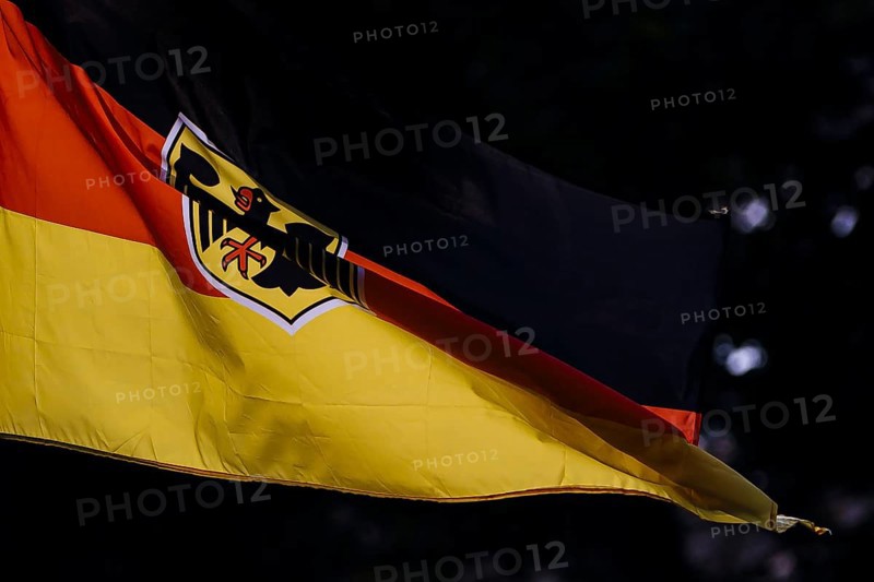 Symbolic photo. The national flag of the Federal Republic of Germany with a federal eagle fluttering in the wind against the light. Berlin, 21 August 2024