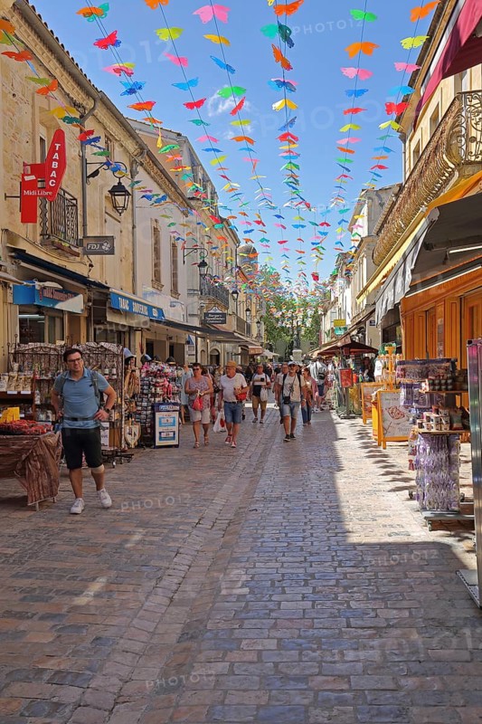 People strolling and shopping in the Grand Rue Jean Jaurès, decoration, pennant chain, tourists, shop, shops, street pub, Jaures, crowd, view from above, Aigues-Mortes, Gard, Camargue, Provence, France, Europe
