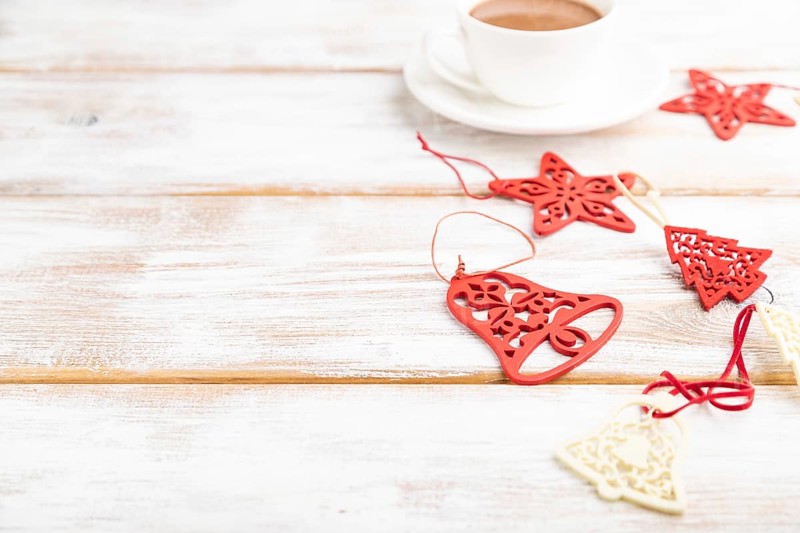Christmas or New Year composition. Decorations, red stars, bells, on a white wooden background. Side view, copy space, selective focus