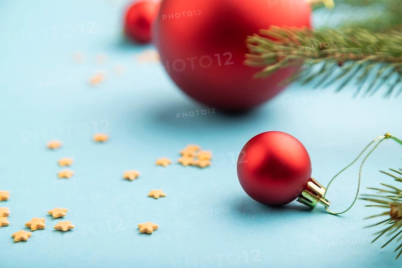 Christmas or New Year composition. Decorations, red balls, fir and spruce branches, on a blue paper background. Side view, copy space