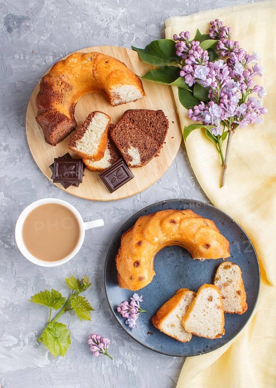 Cakes with raisins and chocolate and a cup of coffee. lilac flowers on a gray concrete background, top view, flat lay
