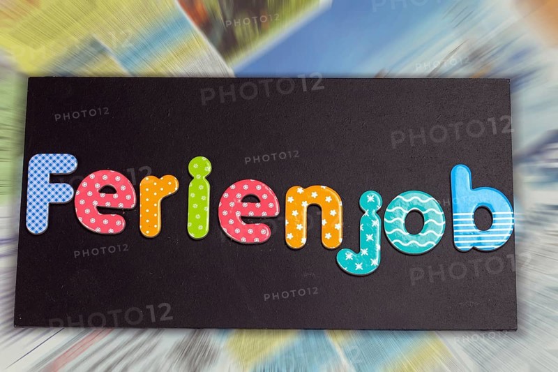 Symbolic image of a holiday job: board with the inscription FERIENJOB in front of the job adverts in a newspaper