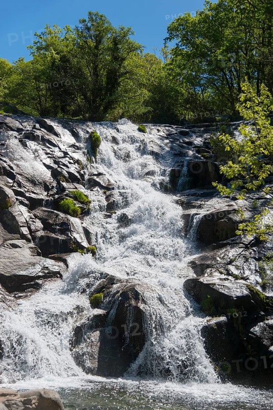 Wild water flows over staggered rocks in the middle of a green forest on a bright summer day, Cascada del Calderon, Piornal, Cáceres, Cacares, Extremadura, Spain, Europe
