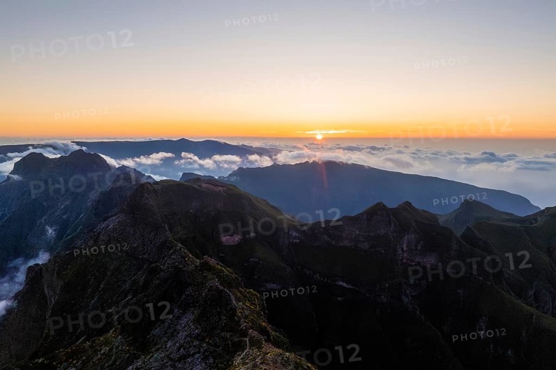 Aerial drone view of mountains over clouds near Pico Ruivo on sunset. Madeira island, Portugal, Europe