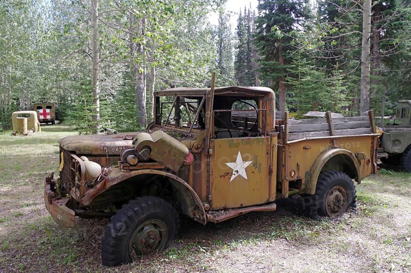 A rusty old army vehicle from the 1940s with a star, surrounded by trees in a forest, former army camp, Yukon, Discovery Lodge, Alaska Highway, Yukon Territory, Canada, North America