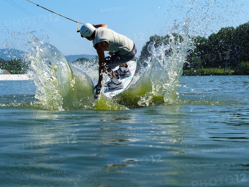 Young man jumping with wakeboard into the lake, water sports, water skiing in wakepark, Stráž pod Ralskem, Czech Republic, Europe