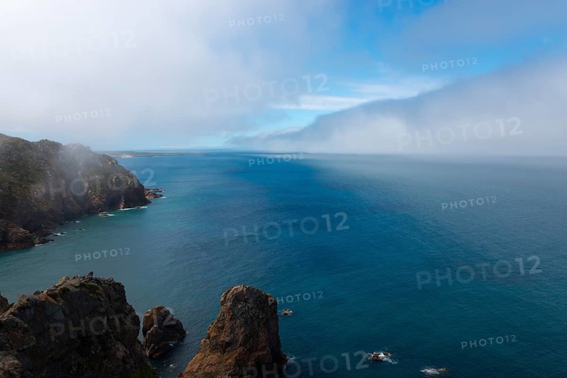 Steep cliffs jut into the blue sea under a cloudy sky, fog, Cape Cabo da Roca, westernmost point of mainland Europe, Atlantic coast, Sintra, Lisbon, Lisboa, Portugal, Europe
