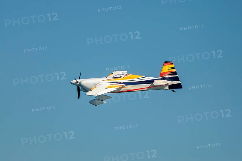 Stunt aerobatic plane performing stunts in blue sky. Concept of speed, difficulty, precision, risk, challenge