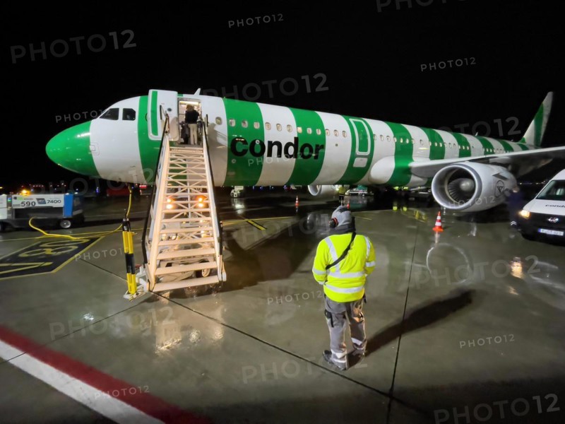 Night shot of Condor aircraft plane Airbus A321 standing landed in parking position on apron apron of airport with mobile stairs for passengers leaving holiday plane via gangway at front exit front door of jet plane, Airport DUS Düsseldorf, Germany, Europe
