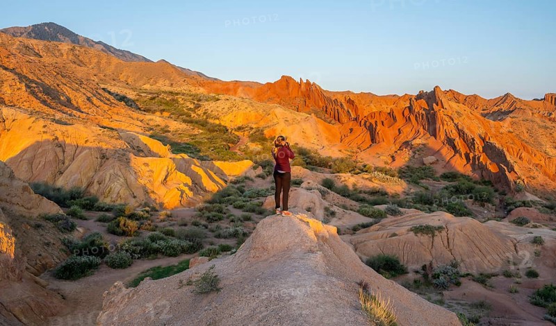 Hiker between red rocks, canyon of eroded sandstone formations, red and orange sandstone rocks, fairytale gorge, Skazka, Tosor, Kyrgyzstan, Asia