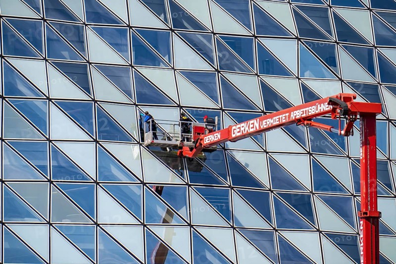 Building cleaners cleaning window panes, cleaning a facade, lorry working platform of the German rental company Gerken, the Antwerp Port Authority building, Havenhuis, former fire brigade barracks in the harbour, renovated and with an attached glass structure, in the shape of a ship's hull, administrative headquarters of the Antwerp Port Authority, designed by Zaha Hadid, Antwerp, Flanders, Belgium, Europe
