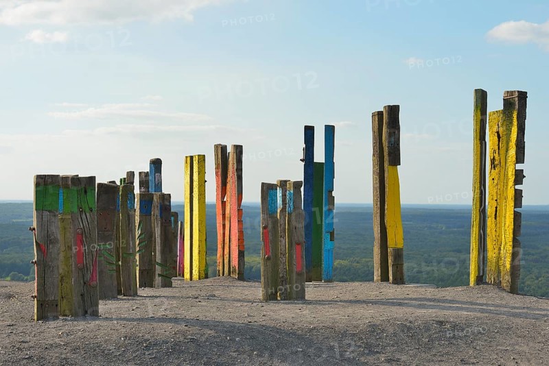 A creative art installation of colourfully painted wooden posts with abstract patterns against a grey sky, Haniel slagheap, Bottrop, Oberhausen, Ruhr area, North Rhine-Westphalia, Germany, Europe