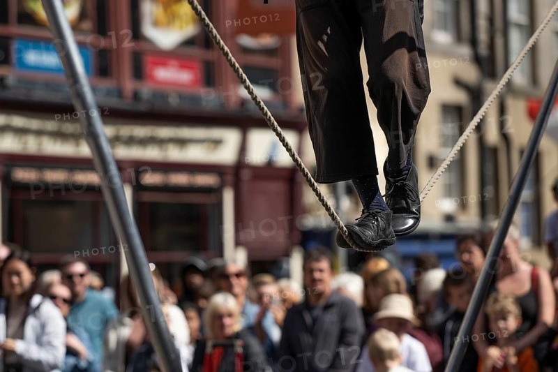 Feet balancing on rope, street performers and spectators at a high-wire acrobatics performance, world's largest cultural festival The Fringe, High Street, Edinburgh, Scotland, United Kingdom, United Kingdom, Europe