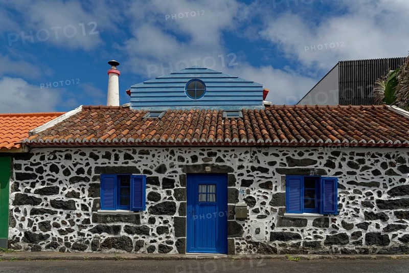 Former whaler's stone house with blue shutters and door, traditional tiled roof, narrow chimney, blue sky with clouds, Capelas, Sao Miguel Island, Azores, Portugal, Europe