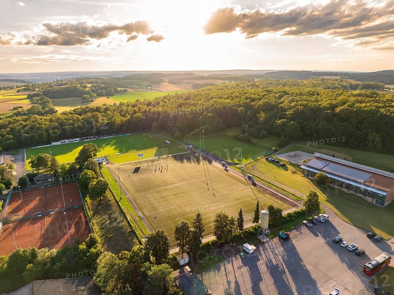 Aerial view of a sports field with football pitch and tennis courts, surrounded by forest and fields at sunset, Gechingen, Black Forest, Germany, Europe