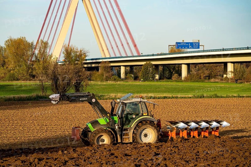 Farmer ploughing a field, tractor with plough, near Neuss, Fleher motorway bridge, A46, North Rhine-Westphalia, Germany, Europe