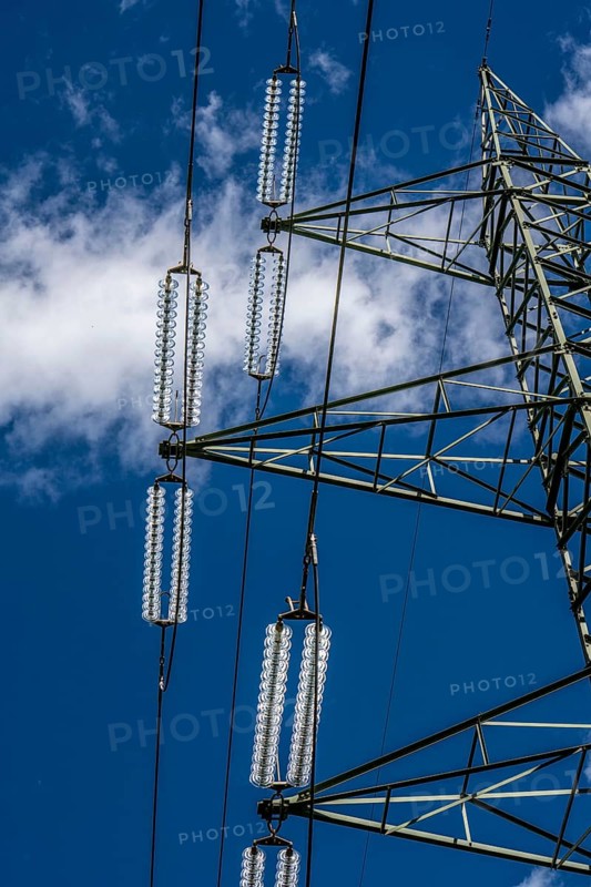 Insulators made of glass on a high-voltage line, they hang on the pylons as a suspension device between the pylon and the live, non-insulated cable, extra-high voltage line, symbolic image energy