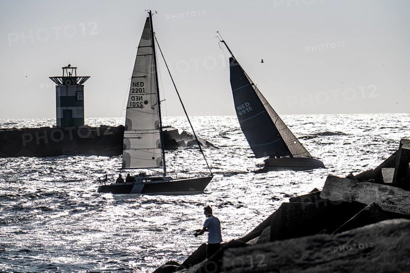 Sailing boat leaving the harbour of Scheveningen, lighthouse at the harbour entrance, Netherlands