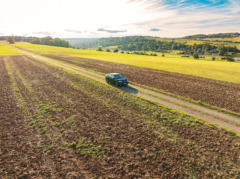 Black car on a rural country lane between fields in a vast rural landscape, car sharing, VW ID5, Calw, Black Forest, Germany, Europe