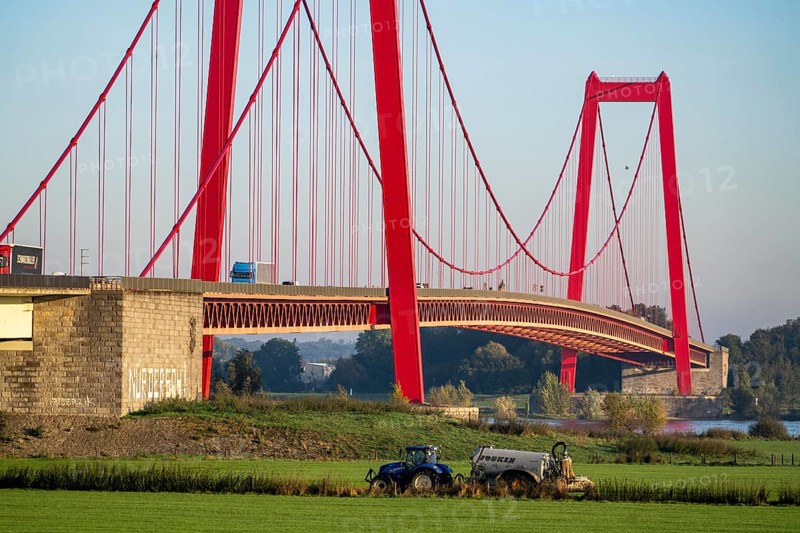The Rhine bridge Emmerich, federal road B220, longest suspension bridge in Germany, is currently being renovated, bridge damage, farmer with tractor brings liquid manure onto the field, Lower Rhine, North Rhine-Westphalia, Germany, Europe