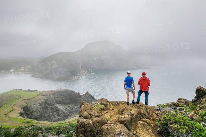 Aerial view, drone photo: Two men standing in the fog on a cliff above Bottle Cove, Bottle Cove Provincial Park, Bay of Islands, Newfoundland, Canada, North America