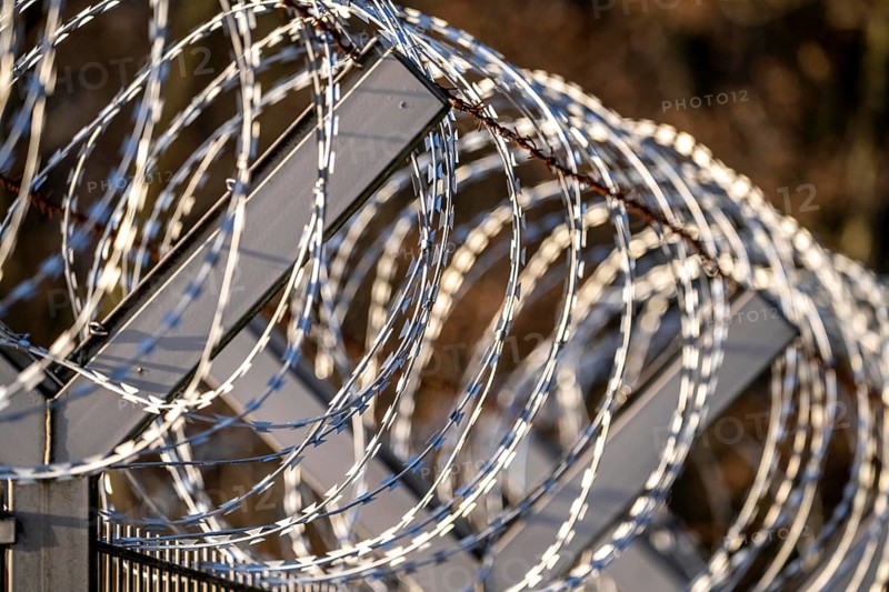 Symbolic image security, S-wire rolls, NATO wire, on a fence top, demarcation of a property, prevention of unauthorised access, strip steel wire with sharp blades