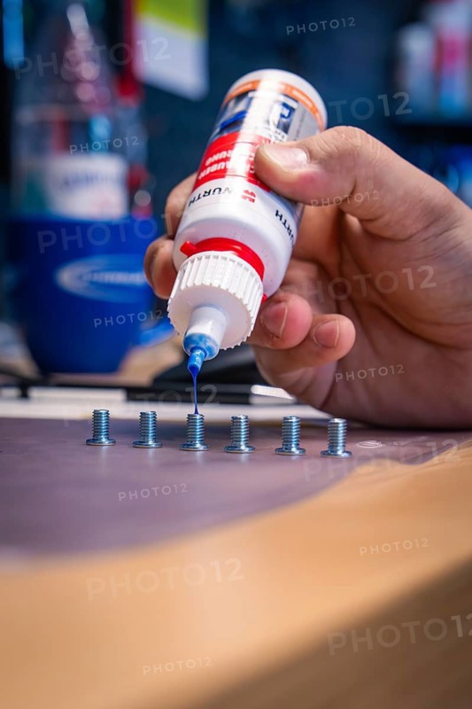Hand applying blue liquid to screws on a workbench, Waldbike Manufaktur, bicycle workshop, Calw, district of Calw, Black Forest, Germany, Europe
