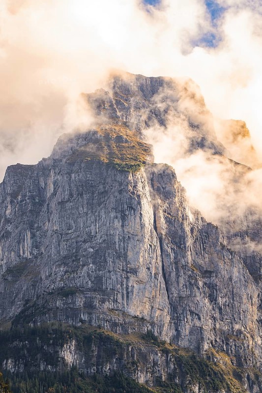 Impressive rock face rises into the sky, enveloped by light clouds, Lake Brienz, Switzerland, Europe