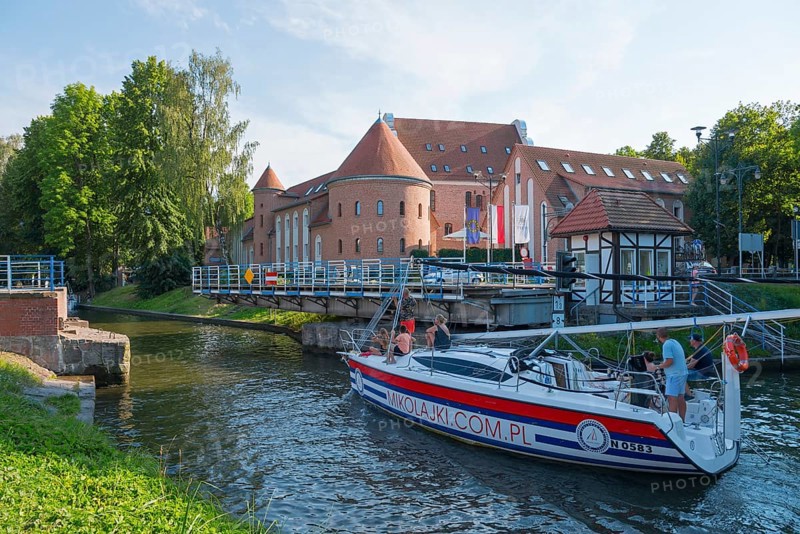 Sailing boat in front of a large brick building near a bridge in summer, swing bridge, Lötzen Canal, Gizycko, Warminsko-Mazurskie, Warminsko-Mazurskie, Poland, Europe