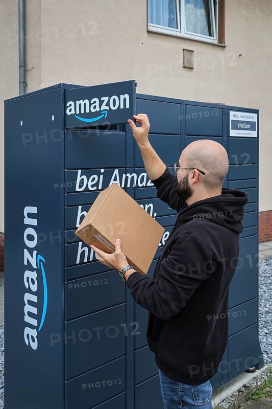 Bottrop, North Rhine-Westphalia, Germany, Amazon, Amazon Locker, Amazon Hub, Packstation, parcel station, pick-up station, customer picks up parcel, a customer opens a flap with an app on his mobile phone and removes his parcel, Europe