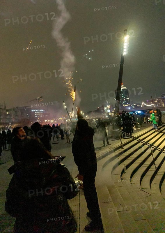 Person launches firework rocket from his hand, New Year's Eve 2025 on the Elbe promenade in Hamburg, at the harbour, on the Elbe, fire brigade of many thousands of people, Jan Fedder promenade
