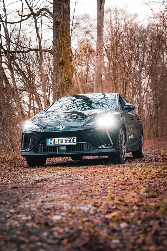 Black car on a forest path with shining headlights in an autumnal ambience, e-car sharing vehicle from Deer Mobility, Gechingen, Black Forest, Germany, Europe