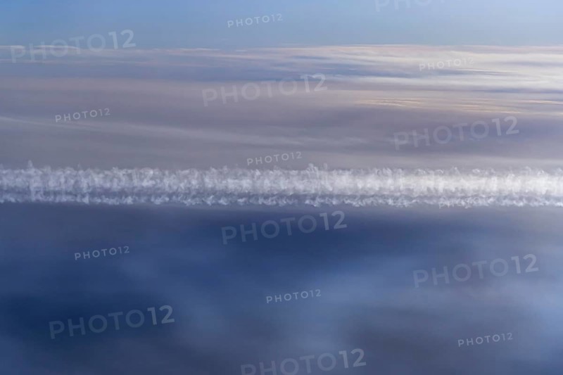 View of the Persian Gulf from the aeroplane window. Sun and clouds over the sea. Aeroplane above the clouds with vapour trails. Flight with the airline Etihad. Abu Dhabi, United Arab Emirates, UAE, Asia