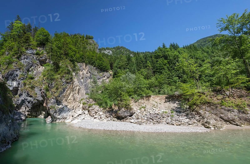 The Lammer creek is flowing fast through the Lammerklamm on a sunny hiking day. Blue sky, turquoise water and green trees