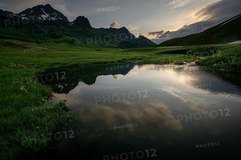 Summit in the morning light with dramatic clouds and stream in the foreground, Lech, Lechquellengebirge, Vorarlberg, Austria, Europe