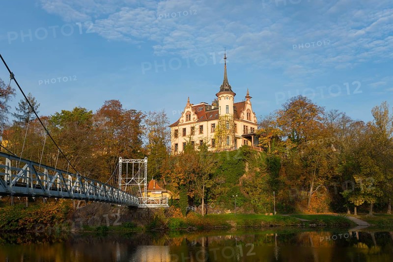 Castle on a wooded hill with adjoining bridge and river in autumn, Gattersburg Castle, suspension bridge, Mulde River, Grimma, Leipzig, Saxony, Germany, Europe
