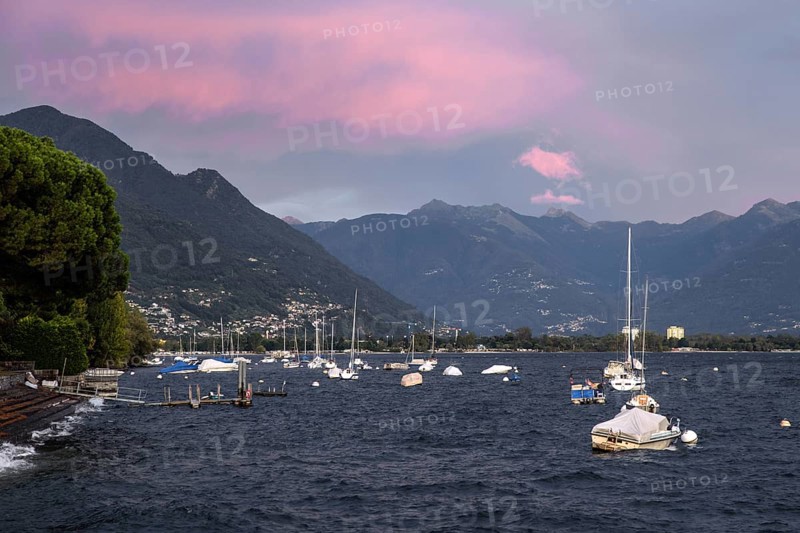 Boats lying in the water, Locarno, Lake Maggiore, clouds coloured by the evening light in the background, Canton Ticino, Switzerland, Europe