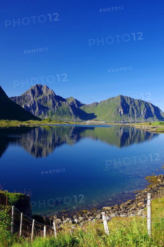 Mountains reflected in the calm waters of an inlet, Leknes, Vestvågøy, Lofoten, Nordland, Norway, Europe