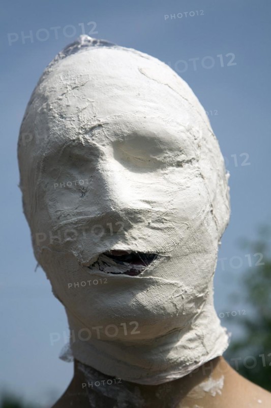 Model released young man's face covered in white bandage tape as art project