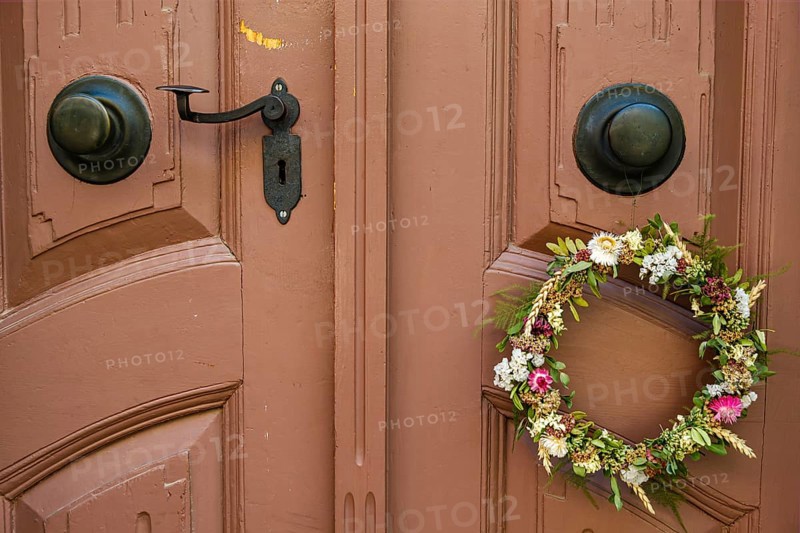 Detail of an antiquated front door with floral wreath in a building on the Krämerbrücke in the historic city centre of Erfurt, Thuringia, Germany, Europe