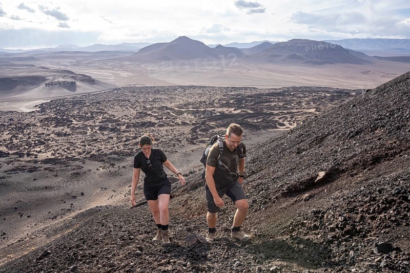 Two hikers climb up a rocky volcanic slope, Argentina, Volcanoes, Lava field, Antofagasta, South America