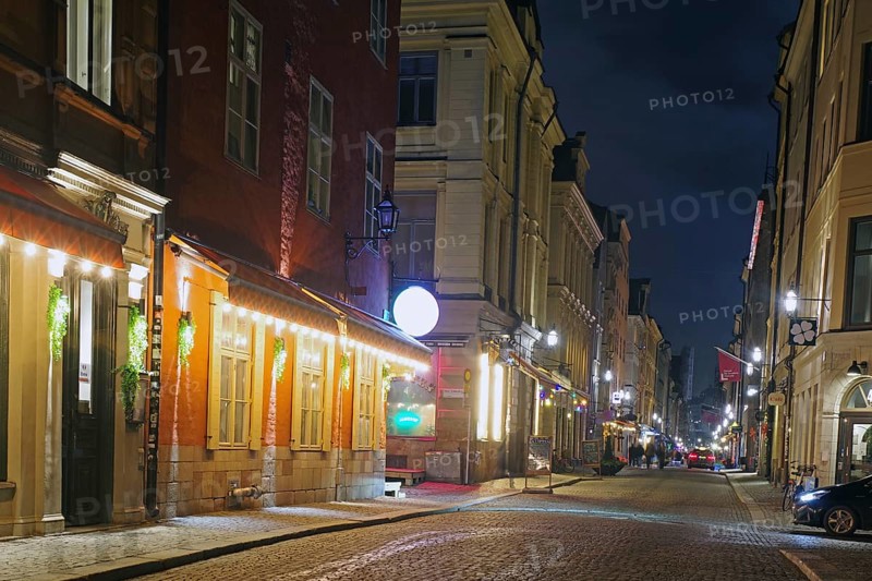 Night shot of a cosy street with old buildings and warm lantern light in a city, winter, Gamla Stan, Old Town, Stockholm Sweden