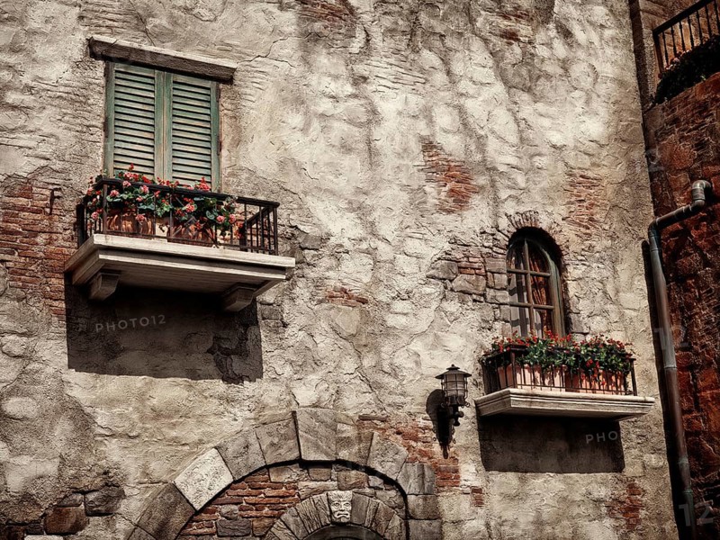 Old rustic house windows with flowers, antique architecture in Venetian style sepia toned